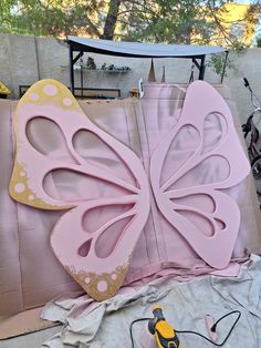 a large pink butterfly sitting on top of a piece of cardboard next to a pair of scissors