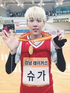 a young man is standing on a basketball court with his hands in the air and wearing a medal around his neck