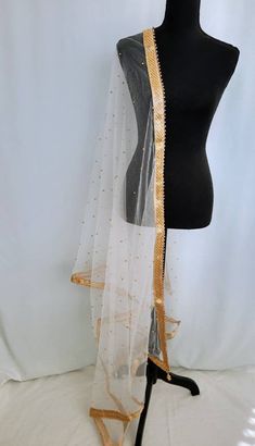 Very beautiful premium quality White net Dupatta embellished with golden beads on all 4sides and golden  pearls attached on Dupatta. Pair this Dupatta with your ethnic outfits. Finest quality white net with golden pearls. This unique rich look Dupatta compliments your attire. The Dupatta has golden bead tassels with big pearls Length 2.50metres Very attractive dupatta Color White( border gold) Gold Saree With Sheer Dupatta For Wedding, Gold Traditional Wedding Wear With Dupatta, Gold Organza Lehenga With Cutdana, Gold Organza Lehenga With Cutdana Details, Gold Saree With Sheer Dupatta In Traditional Drape, Festive Gold Lehenga With Sheer Dupatta, Gold Semi-stitched Saree With Sheer Dupatta, Gold Kundan Traditional Wear With Dupatta, Gold Saree With Dupatta For Diwali