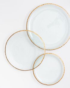 three white plates with gold rims sitting on top of each other in front of a white background