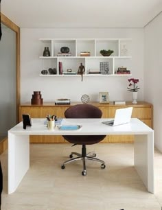 a white desk with a laptop on top of it in front of a book shelf