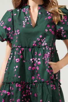 Say hello to the dress you can wear to almost any occasion. A classic pink floral motif lays against an emerald color to decorate the Anissa Floral Babydoll Dress. It features puff sleeves around the shoulders and three layers of tiers to compliment the dress. A split neckline is highlighted by billowy short sleeves in this mini dress. - Split neckline- Bubble sleeves- Babydoll- Pocket- Color: Emerald multiSize + Fit - Model is 5'8" and wearing size XS- Measurements taken from size S - Chest: 19 Green Floral Mini Dress With Ruffles, Green Feminine Tiered Dress, Feminine Green Tiered Dress, Green Floral Print Mini Dress With Short Sleeves, Green Floral Print V-neck Dress, Feminine Green Mini Dress With Ruffles, Green V-neck Dress With Floral Print, Green V-neck Floral Print Mini Dress, Green Floral Print V-neck Mini Dress