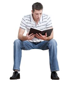 a young man sitting on a stool reading a book, isolated against a white background photo