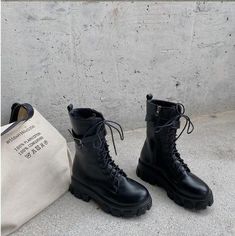 a pair of black boots sitting next to a white bag