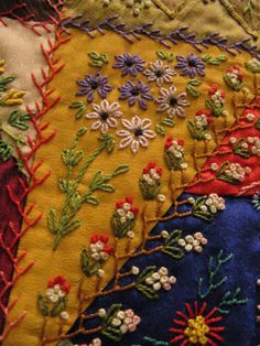 an embroidered pillow with flowers and leaves on it