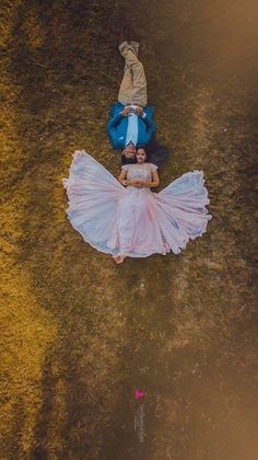 two people laying on the ground with their arms around each other and one person wearing a dress