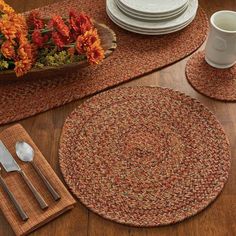 placemats, plates and silverware on a wooden table with orange flowers in the center