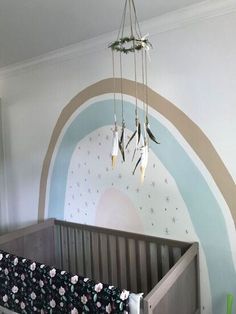 a baby's room with a crib in the middle and a rainbow painted on the wall