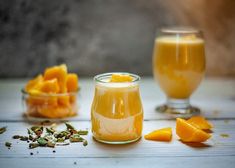 a glass jar filled with liquid next to sliced oranges and other food on a table