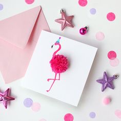 a pink flamingo pin sitting on top of a card next to some star decorations