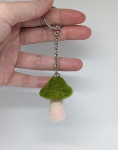 a hand holding a tiny keychain with a small mushroom on it's side