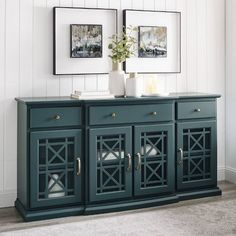 a blue sideboard with two pictures on the wall above it and an area rug in front of it