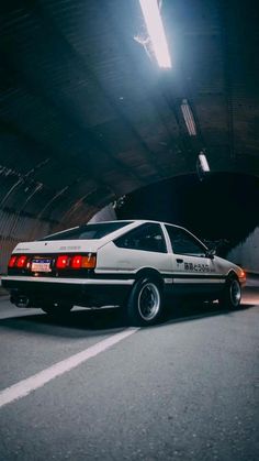 a white police car parked in a parking garage next to a light on the ceiling