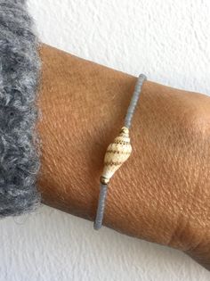 a close up of a person's arm wearing a bracelet with a shell on it