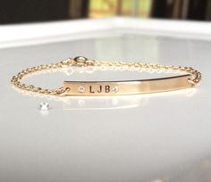 "Beautiful slender gold nameplate bracelet with 2 petite white diamond czs surrounding your intials. I hand stamp the initials and hand drill and set each stone. This is a delicate everyday gold bracelet that is a great gift for you, your friends or family! 14 k gold fill is used for the chain, bar and spring ring clasp. Gold bar dimensions: 3mm x 35mm You can have up to 5 characters stamped on this bracelet. Bracelet Sizing In order to get a nice fit, I recommend measuring the circumference of Everyday Gold Bracelet, Bar Bracelet Personalized, Diamond Bar Bracelet, Lingot D'or, Nameplate Bracelet, Custom Engraved Necklace, Gold Bar Bracelet, Gold Disc Necklace, Handwriting Jewelry