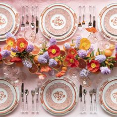 the table is set with plates, silverware and colorful flowers on each one plate