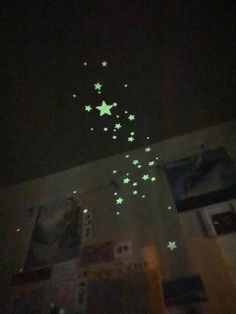 stars glow in the night sky above a room with pictures and posters on the wall