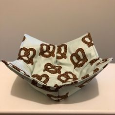 a cloth bowl sitting on top of a white table next to a brown and white wall