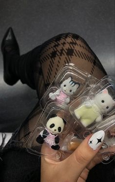 a woman with her legs crossed holding four small plastic animal figurines in their hands