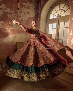 a woman in a red and green dress is dancing with her arms out to the side