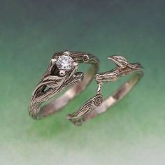 two silver rings with leaves and a diamond on each ring, set against a green background