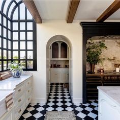 a kitchen with black and white checkered flooring next to an arched window in the wall