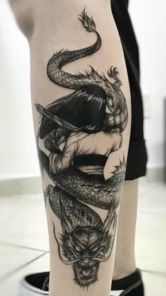 a woman's leg with a dragon and snake tattoo on the side of her leg