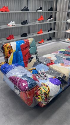 a couch made out of shirts in a room with shelves full of shoes and other items