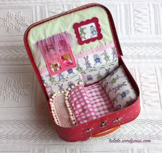 an open pink suitcase sitting on top of a white lace tablecloth covered bedding