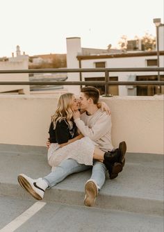 a man and woman are sitting on the steps kissing each other while they both have their arms around each other