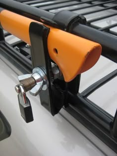 an orange and black handlebar attached to a white vehicle with metal bars on it