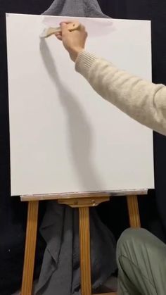 a person is holding a paintbrush and drawing on a white board