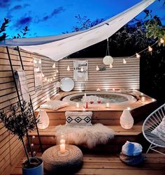 an outdoor hot tub with candles on the side and lights hanging from it's sides