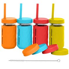 four different colored mason jars with lids and straws next to each other on a white background