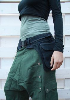 a woman wearing green pants and black shirt holding her cell phone to her hip pocket