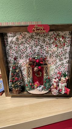 a christmas scene in a wooden frame with presents and trees on the shelf next to it