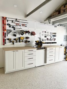 a garage with white cabinets and tools hanging on the wall