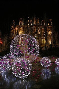 the lights are on and there is a fountain in the middle of the park at night