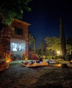 an outdoor movie is being projected on the screen in front of a house at night