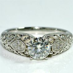 a white gold engagement ring with an intricate filigreet design on the band