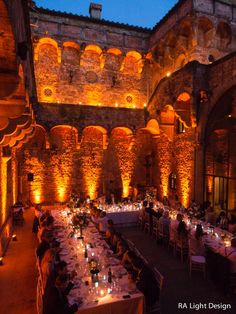 an indoor dining area with tables and chairs lit up at night, surrounded by stone walls