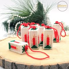 four white and red crocheted christmas gifts on a tree stump with pine branches in the background