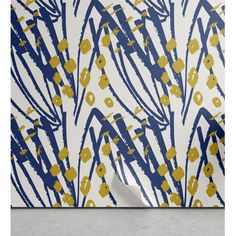 an abstract painting with blue and yellow flowers on white paper, in front of a gray wall