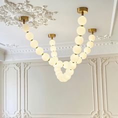 a chandelier hanging from the ceiling in a room with white walls and gold trim