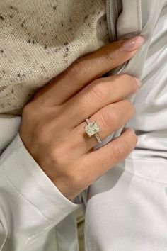 a woman's hand with a diamond ring on her left hand, and the other hand is wearing a white shirt