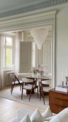 a living room filled with furniture and a dining table surrounded by potted greenery