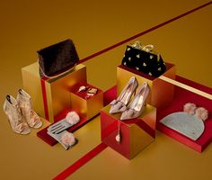 an assortment of women's shoes and purses on display in red boxes with gold stripes