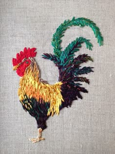 a colorful rooster is on the side of a piece of fabric that has been stitched onto it