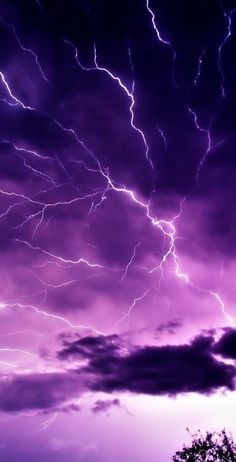 the sky is filled with lightning and purple hues, as seen from an airplane