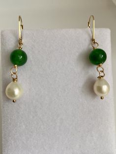 "At an auction last year in Maine, I was able purchase these exquisite pearls. The label on the sleeve indicated that they date back to the 1980s. They boast a stunning creamy white iridescent nacre, radiating elegance. The hand-carved Brazilian emeralds, measuring 12mm, are a recent addition, beautifully complementing the pearls. The lever back is made of 14k gold filled, with a 14k gold stamp, manufactured in the USA. As the birthstone for May, the emerald holds significant meaning. Symbolizing rebirth, it is believed to bestow upon its owner the gifts of foresight, good fortune, and eternal youth. The word \"emerald\" derives from the Greek term \"smaragdus,\" which quite literally translates to \"green,\" reflecting its captivating hue." Classic Jade Jewelry For May Birthstone, Classic Green Pearl Drop Jewelry, Green Pearl Dangle Jewelry, Green Round Pearl Drop Jewelry, Green Pearl Drop Jewelry As Gift, Green Dangle Pearl Earrings For Anniversary, Green Pearl Drop Jewelry For Gifts, Elegant Green Jewelry With Pearl Charm, Classic Jade Jewelry For Wedding